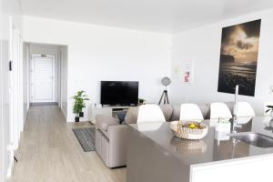 a white living room with a couch and a tv at Casa Pedra de Sal in Ribeira Grande
