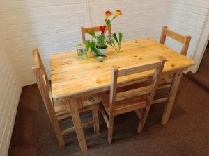 uma mesa de madeira com duas cadeiras e flores em Serendipity-on-Symmonds Cottage em Howick