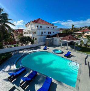 Una gran piscina con sillas azules y un edificio. en C-Roy Estate, en Kupuis