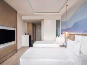 a hotel room with two beds and a flat screen tv at Novotel Chandigarh Tribune Chowk in Chandīgarh