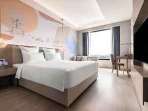a bedroom with a large white bed and a desk at Novotel Chandigarh Tribune Chowk in Chandīgarh