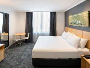 una habitación de hotel con una cama y una mesa en Mercure Sydney Bankstown, en Bankstown