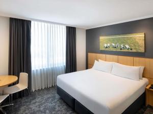 Una habitación de hotel con una cama grande y una mesa. en Mercure Sydney Bankstown, en Bankstown 71 fotos más