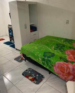 ein Schlafzimmer mit einem grünen Bett, das mit Rosen verziert ist in der Unterkunft Kitnet Dream House 4 in Bayeux