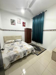 a bedroom with a bed and a blue curtain at Homestay Bandar Sejahtera in Pokok Sena