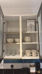 a kitchen cabinet filled with bowls and other dishes at Huddersfield City Center Retreat - New Images coming soon in Huddersfield