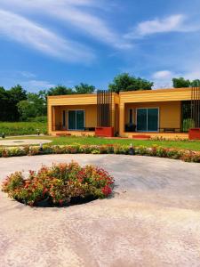 a yellow building with flowers in front of it at ห่มฟ้าโพธิ์แค้มป์ปิ้ง 