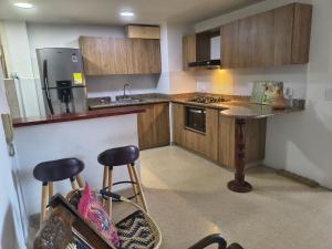a kitchen with a counter and two stools in it at Habitación con cama nueva semidoble y balcón privado cerca del parque in La Ceja