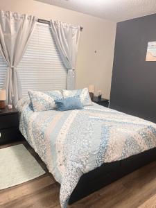 a bedroom with a bed with a blue comforter and a window at Cozy-1bedroom suite near Downtown Lawrenceville in Lawrenceville