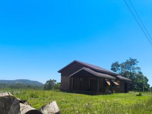 a brown barn in a field with some rocks at Casa de campo da Prof Fabi in Montenegro