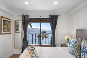 a bedroom with a bed with a view of the ocean at Lauloa 403 · LOA 403 Fully Remodeled Direct Oceanfront 2BD in Wailuku +55 photos