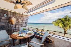 a dining room with a table and chairs and a view of the ocean at Kulakane 310 · KK 310 Updated BeachFront 2BD w AC Pool in Kahana