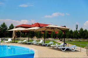 ein Swimmingpool mit Sonnenschirmen und Liegestühlen neben einem Swimmingpool in der Unterkunft Jansaya Resort база отдыха Жансая in Aleksandrovka