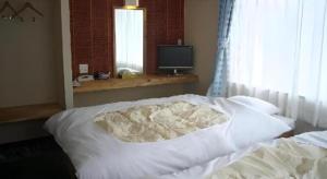 a white bed in a bedroom with a television at Business Hotel Tsuwano in Tsuwano
