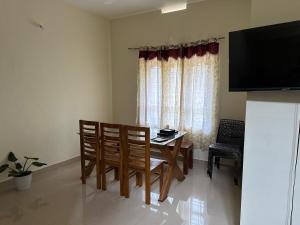 a dining room with a table and chairs and a television at Vathika Villa in Sultan Bathery