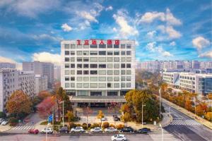 Un gran edificio blanco en una ciudad con coches aparcados. en Hotel Leader Changsha, en Changsha