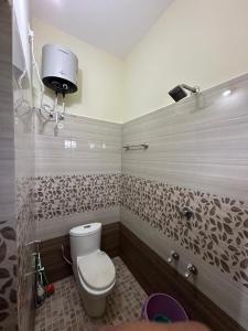 a bathroom with a toilet and a hair dryer on the wall at Vathika Villa in Sultan Bathery