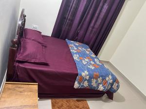 a bed with a purple comforter and a pillow at Vathika Villa in Sultan Bathery