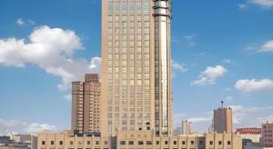 een groot hoog gebouw in een stad met gebouwen bij Dongying Dongsheng Hotel in Kenli