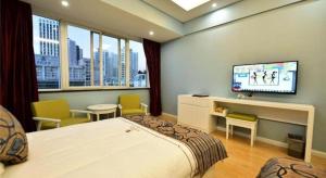 een slaapkamer met een bed en een flatscreen-tv bij Dali Dayu Hotel in Dali