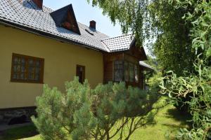 a yellow house with trees in front of it at Góralska Czarcia Chata pod Jałowcem in Stryszawa