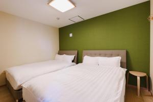 two beds in a room with a green wall at Nihonbashi Moonview in Wada