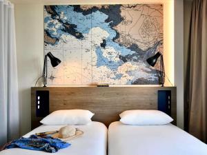 twee bedden in een kamer met een kaart aan de muur bij ibis Styles Saint Nazaire Centre Gare in Saint-Nazaire +73 foto's