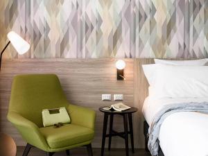 Un dormitorio con una silla verde y una cama. en Novotel Arica, en Arica