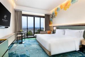 a hotel room with a large bed and a balcony at Holiday Inn Lampung Bukit Randu by IHG in Bandar Lampung