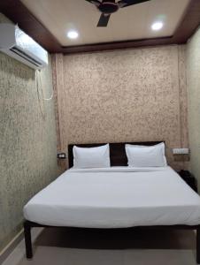 1 dormitorio con cama con sábanas blancas y techo en Hotel Vishnu Inn, en Rewa