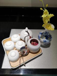 een dienblad met een theeservies en een vaas met bloemen bij Xana Hotelle Xi'an GONG IP South Gate of Zhonglou in Xi'an