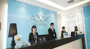 drie mensen zitten aan een balie in een kamer bij Xana Lite·Dunhua Railway Station in Dunhua