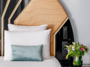 a bed with a pillow and a vase with flowers at The 1932 Hotel & Spa Cap d'Antibes - MGallery Collection in Juan-les-Pins