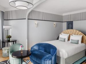 a bedroom with a bed and a blue chair at The 1932 Hotel & Spa Cap d'Antibes - MGallery Collection in Juan-les-Pins +139 photos
