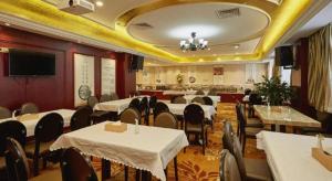 a restaurant with white tables and chairs and a television at Vienna Shanghai Chongming Changxing Island in Dongxing