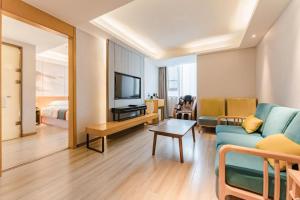 a living room with a blue couch and a television at Jinjiang Metropolo Zhengzhou Songshan Road in Zhengzhou