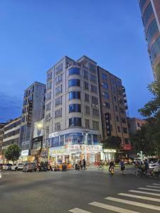 een hoog gebouw in een stadsstraat met mensen ervoor bij PAI Hotel·Huazhou Bus Terminal in Dongshan