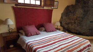 um quarto com uma cama grande e uma cabeceira vermelha em Casa Rural El Traspatio em Granadilla de Abona