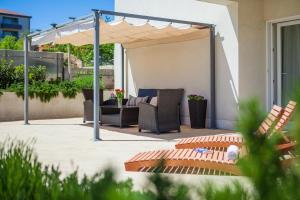 ドゥゴポイエにあるFerienhaus In Dugopolje Mit Beheiztem Poolのパティオ(椅子2脚、パラソル付)