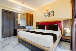 a bedroom with a large bed with a red headboard at Super Townhouse Lighthouse Beach Formerly Neel Sagar in Puri +24 photos