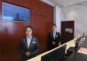 twee vrouwen in pak staand in een kantoor bij City Comfort Inn Yingcheng Railway Station Shanghe Square in Yingcheng