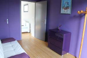 ein Schlafzimmer mit lila Wänden, einem Bett und einer Kommode in der Unterkunft Lumineux T2B a Mont de Marsan in Mont-de-Marsan