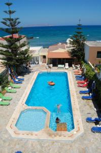 a large swimming pool with chairs and the ocean at Haris Apartments in Kokkini Khanion