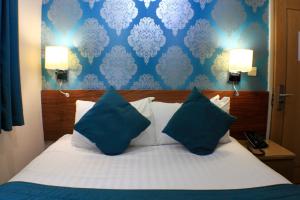 a bed with blue and white pillows in a room at Sheriff Hotel in London