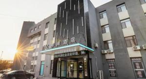 een gebouw met een auto ervoor geparkeerd bij Xana Hotelle Tangshan North Railway Station in Fengrun