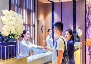 een vrouw die voor de spiegel een man de hand schudt bij Echarm Hotel Qianxi High Speed Railway Station in Qianxi