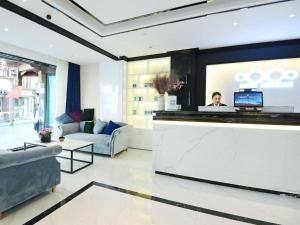 ein Wohnzimmer mit einer Theke und einer Person an einem Computer in der Unterkunft Xana Hotelle Xi'an Zhonglou, Huimin Street Metro Station in Xi'an