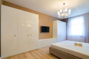 リヴィウにあるRoyal Art-Deco Apartmentのベッドルーム(白い大型キャビネット、テレビ付)