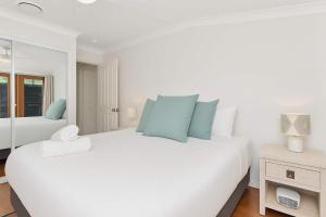 a white bedroom with a large bed with blue pillows at Stay at Shiraz in Pokolbin +15 photos