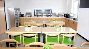 a kitchen with tables and chairs and a refrigerator at Green Tree Inn Express Xingtai Guangzong Development Zone Xingqing Road in Guangzong